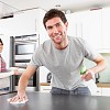 Photo of a man disinfecting a kitchen counter by omgimages/istockphoto.com.