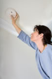 woman checking smoke detector