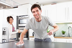 Photo of a man disinfecting a kitchen counter by omgimages/istockphoto.com.