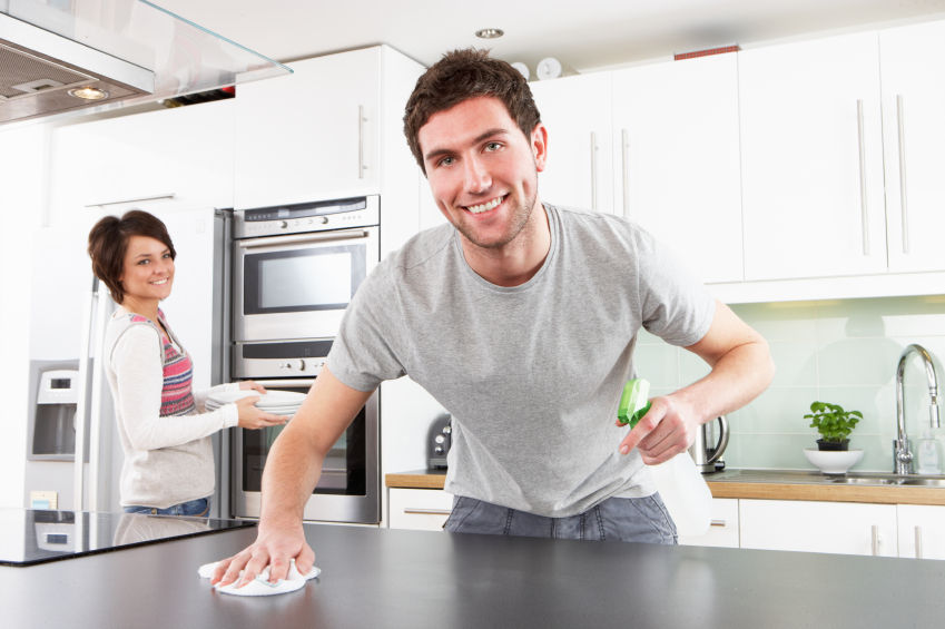 Photo of a man disinfecting a kitchen counter by omgimages/istockphoto.com.