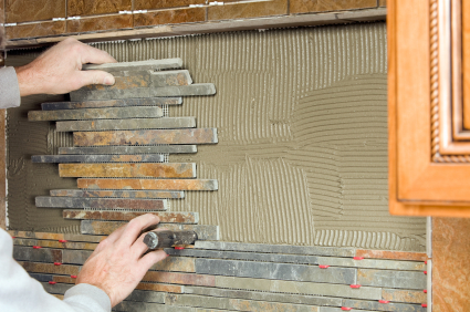 Photo of someone installing a tile backsplash by BanksPhotos/istockphoto.com