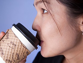 Photo of a woman drinking from a paper coffee cup by emyerson/istockphoto.com