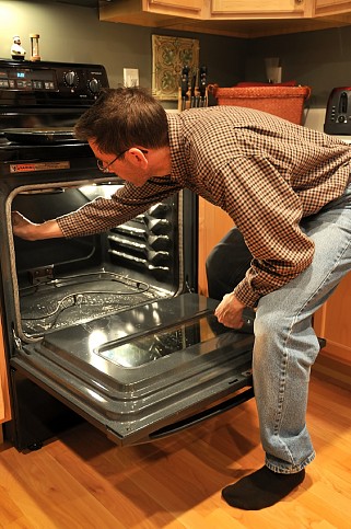 Photo of a man cleaning an oven by akit/istockphoto.com.
