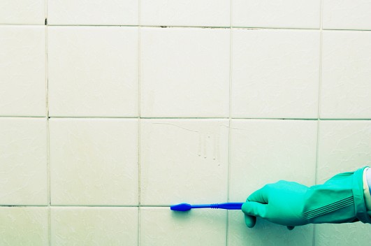 Cleaning mold from shower grout. (creacart/istockphoto.com)