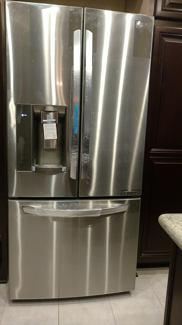 New LG fridge next to our kitchen cabinet